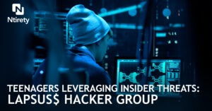 Teenager in hat sitting at computer in dark room hacking.